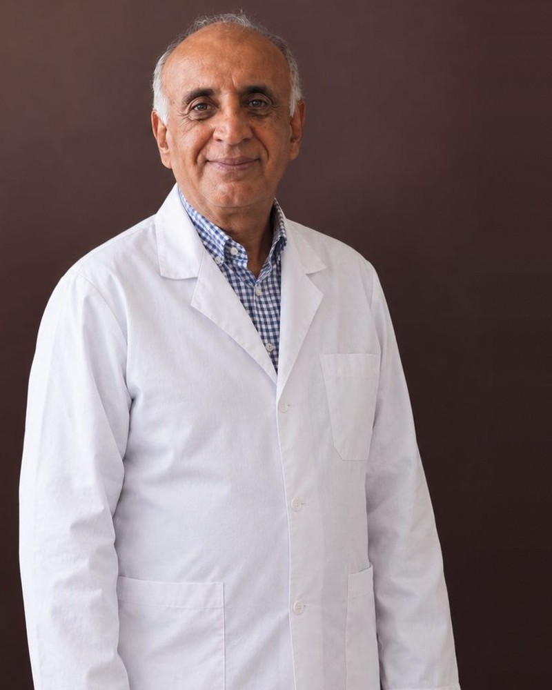 Dr Mohamed Khalil, en blouse blanche, photographié sur un fond brun.